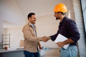 happy,worker,and,his,clients,shaking,hands,at,constriction,site.